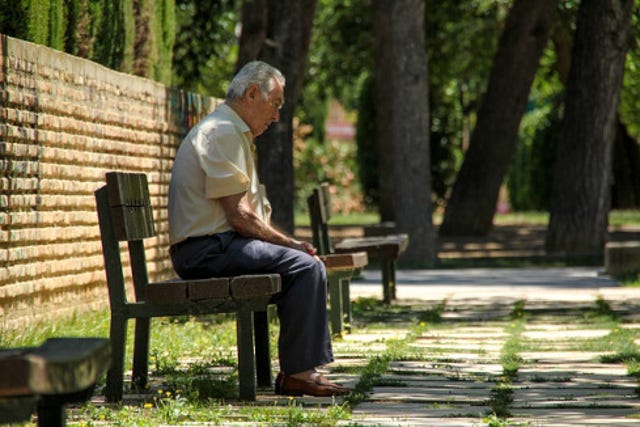 aging gentleman sitting on a park bench