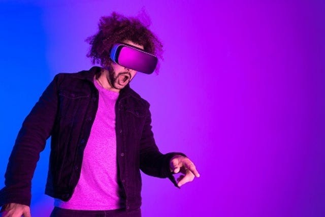 Metaverse concept. Surprised young man touching the air and smiling during VR experience